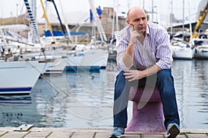 Businessman sitting by expensive sailing boats and yachts in a c