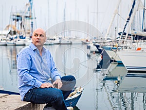 Businessman sitting by expensive sailing boats and yachts in a c