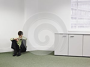 Businessman Sitting On Floor In Corner At Office