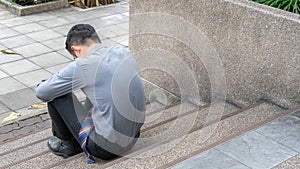 Businessman sitting on the floor pedestrian space. He feel sad worry tired frustrated upset fail after lost work job from office.