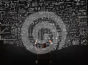 Businessman sitting in front of a blackboard with charts