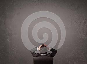 Businessman sitting in front of a wall with copy space