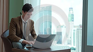 Businessman sitting on furniture working on laptop at ornamented corporate