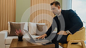 Businessman sitting on furniture working on laptop at ornamented corporate