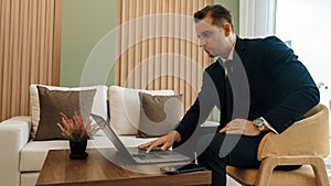 Businessman sitting on furniture working on laptop at ornamented corporate