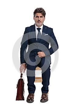 Businessman sitting and grabing his briefcase serious