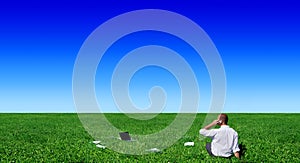 Businessman sitting on green field