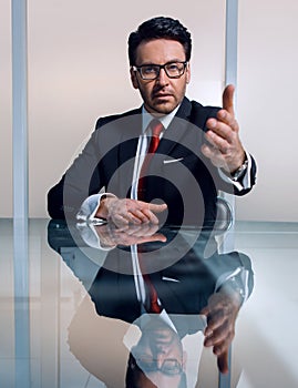 Businessman sitting at his Desk and holding out his hand for a handshake