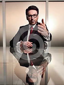 Businessman sitting at his Desk and holding out his hand for a handshake