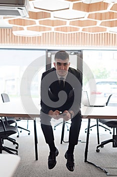 A businessman sitting on his desk, taking a moment to rest and unwind from a demanding workday, displaying a sense of