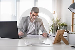 Businessman sitting on his office desk. Analysing reports, worried