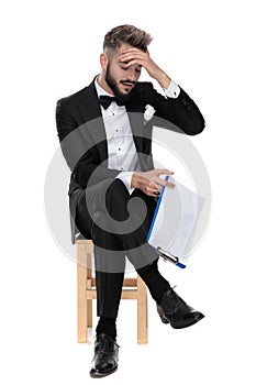 Businessman sitting and holding clipboard while slapping forehead