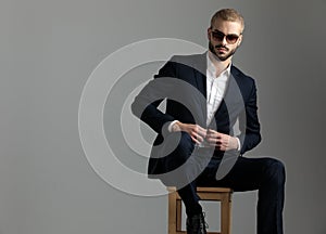 Businessman sitting and holding his jacket`s button confident