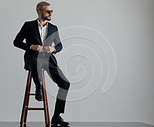 Businessman sitting and holding his jacket`s button looking sideways