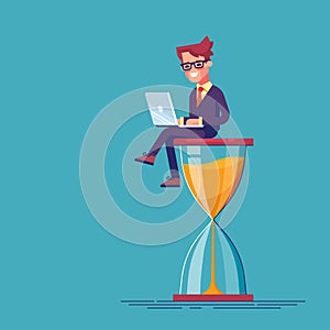Businessman sitting on the hourglass with laptop legs crossed. Business concept of time management and procrastination.