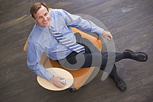 Businessman sitting indoors with cellular phone