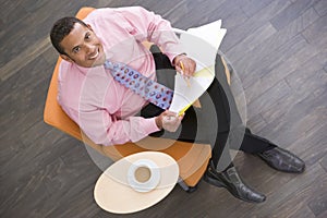 Businessman sitting indoors with coffee and folder