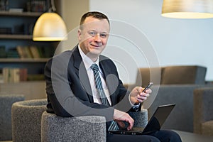 A businessman sitting with laptop and phone photo