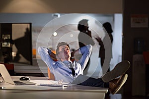 Businessman sitting with legs on desk at office