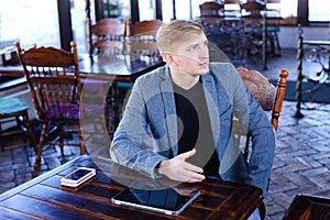 Businessman sitting near table with smartphone and laptop speaki