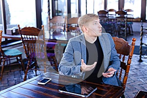 Businessman sitting near table with smartphone and laptop speaki