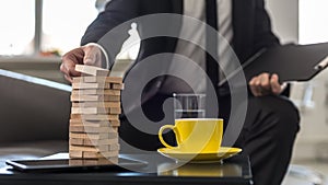 Businessman sitting in office building a tower of stacked blocks