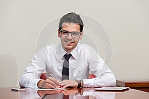 Businessman Sitting At Office Desk Signing A Contract