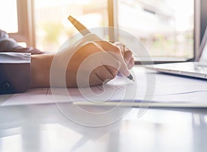 Businessman sitting at office desk signing a contract close up