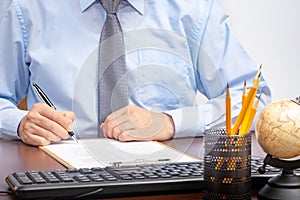 Businessman sitting at office desk signing a contract with shallow focus on signature.