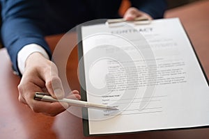 Businessman sitting at office desk signing a contract with shallow focus on signature