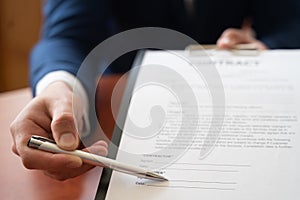 Businessman sitting at office desk signing a contract with shallow focus on signature