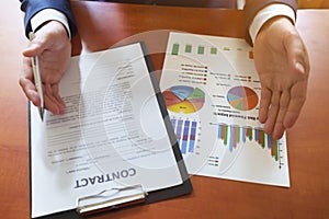 Businessman sitting at office desk signing a contract with shallow focus on signature