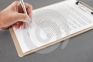 Businessman sitting at office desk signing a contract with shallow focus on signature