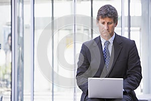 Businessman sitting in office lobby using laptop