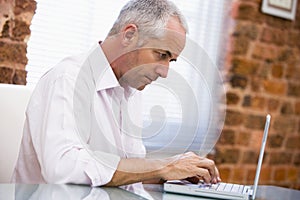 Businessman sitting in office typing on laptop