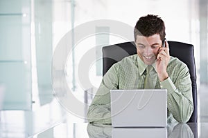 Businessman sitting in office using cellular phone photo