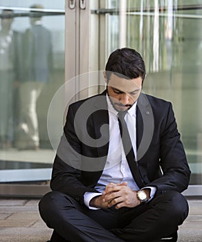 Businessman sitting outside on the curb and waiting