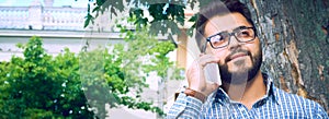 Businessman sitting on park bench with coffee using mobile phone.
