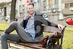 Businessman sitting on a park bench while talking on the phone