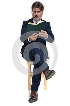 Businessman sitting and reading a book intrigued