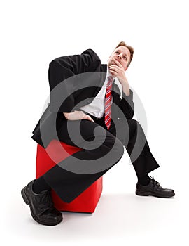 Businessman sitting on red tabouret