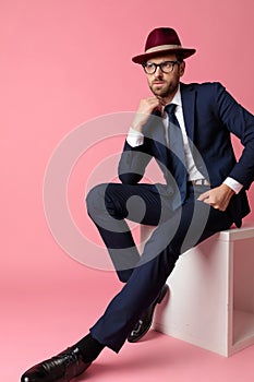 Businessman sitting with resting hands and fixing his collar pensive