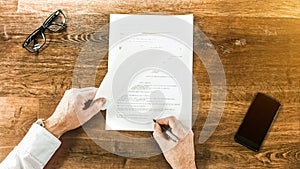 Businessman sitting at shiny office wood desk signing a contract