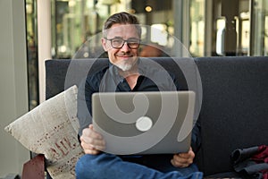 Businessman sitting on sofa working with laptop in office