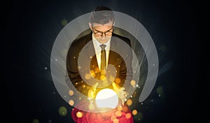 Businessman sitting with sparkling magic ball