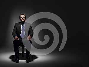 Businessman Sitting In Spotlight