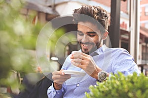 Businessman sitting in street cafe and having coffee brea