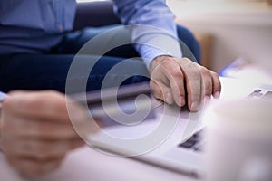 Businessman sitting at table with laptop and documents