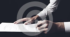 Businessman sitting at table and signing document