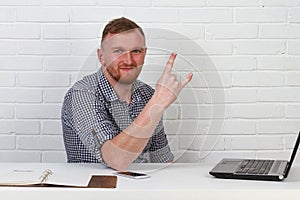 Businessman sitting at the table and working on the computer. It solves important business tasks. He is successful and well-traine